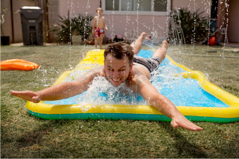man playing in a water slide at home